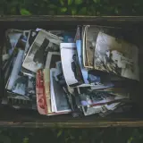 Caja de madera llena de fotos antiguas, como si fueran recuerdos de personas con memoria fotográfica.