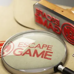 Lupa y sello de "Escape Game" sobre papel, buscando los mejores escape room online.