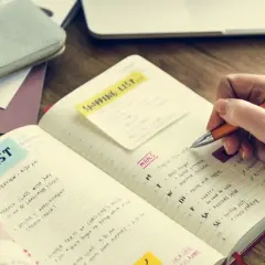 Persona escribe en un diario para aprender a escribir, con listas de tareas y comidas.