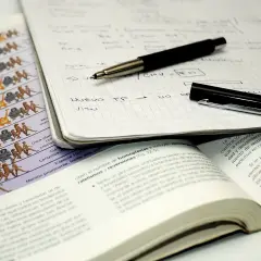 Apuntes para estudiar: cuaderno con notas, bolígrafo, libro abierto y lámina de evolución.