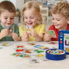 Niños sonríen mientras aprenden a leer jugando con cartas de animales. El juego LOCO fomenta la creatividad y el aprendizaje.