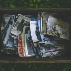 Caja de madera llena de fotos antiguas, como si fueran recuerdos de personas con memoria fotográfica.