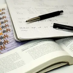 Cuaderno con notas, bolígrafo y libro abierto. El método Cornell se aplica en el estudio de la evolución, como muestra la imagen.