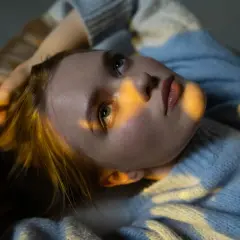 Joven con luz dorada en el rostro, reflexionando sobre técnicas para eliminar pensamientos catastróficos.