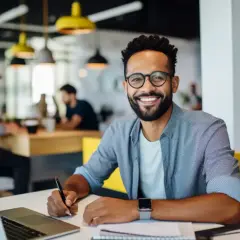 Hombre sonriente trabaja en su portátil, aplicando **técnicas de aprendizaje** en un espacio moderno.