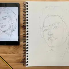 Aprendiendo como dibujar retratos. Boceto a lápiz de un rostro en un cuaderno, con una tablet mostrando el modelo.