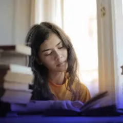 Joven concentrada estudiando, rodeada de libros, buscando técnicas para como memorizar fechas importantes.