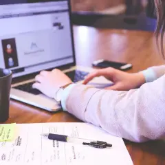 Persona trabajando en portátil, con taza y notas. Su memoria cristalizada se forma con cada idea plasmada.