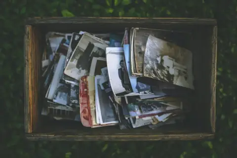 Caja de madera llena de fotos antiguas, como si fueran recuerdos de personas con memoria fotográfica.