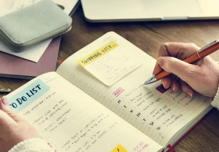 Persona escribe en un diario para aprender a escribir, con listas de tareas y comidas.
