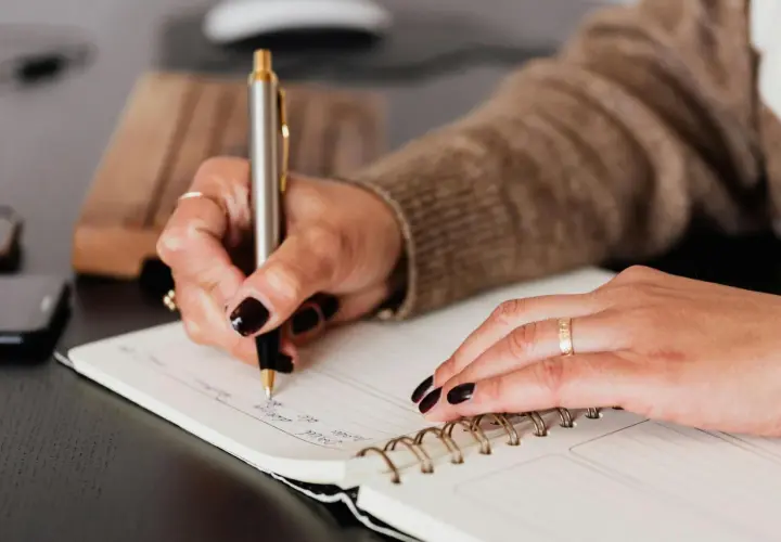 Mano escribiendo en un cuaderno, un paso más para aprender a escribir.