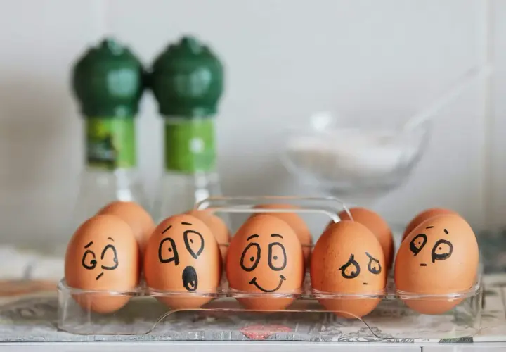 Huevos en una caja con caras dibujadas, mostrando una divertida actividad de las emociones.