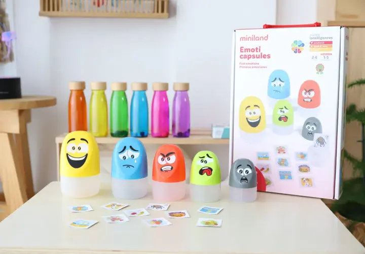 Juguetes para la inteligencia emocional infantil: cápsulas con caras de emociones y tarjetas.