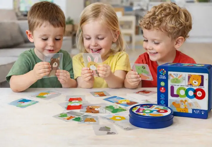 Niños sonríen mientras aprenden a leer jugando con cartas de animales. El juego LOCO fomenta la creatividad y el aprendizaje.