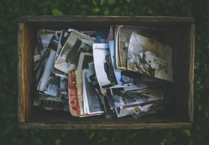 Caja de madera llena de fotos antiguas, como si fueran recuerdos de personas con memoria fotográfica.