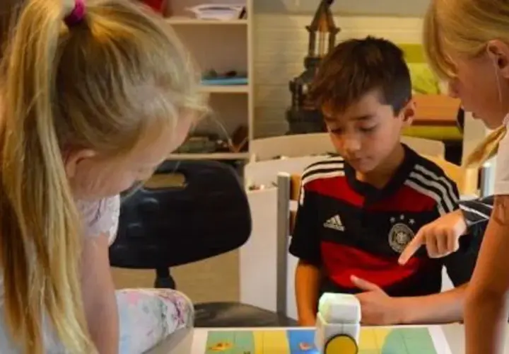 Niños concentrados en deberes de verano originales, programando un robot.