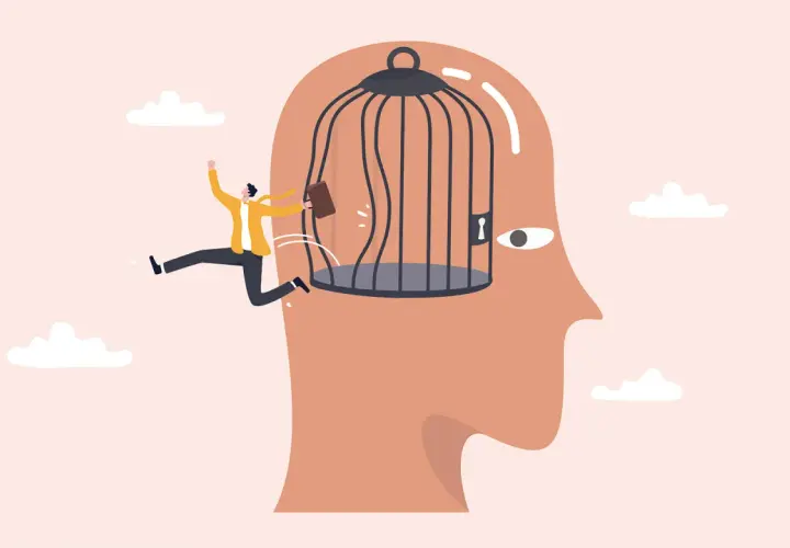 Hombre escapa de una jaula dentro de una cabeza, simbolizando la superación de una mente bloqueada.