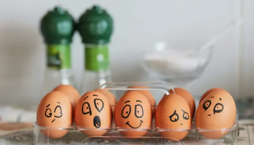 Huevos en una caja con caras dibujadas, mostrando una divertida actividad de las emociones.