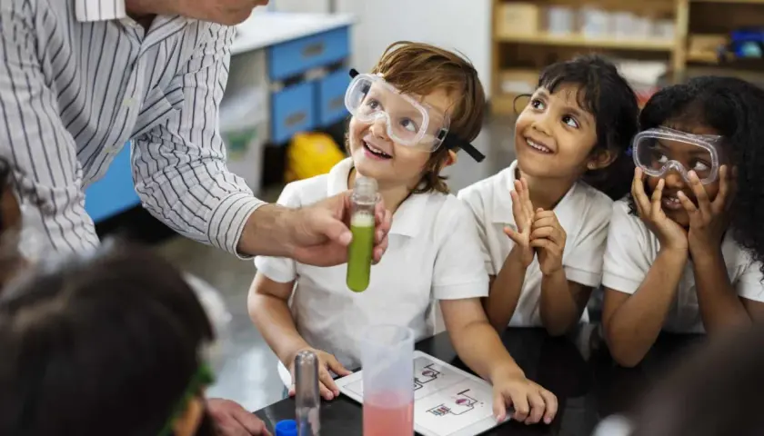 Niños con gafas de seguridad observan un experimento, aprendiendo qué es un STEM.