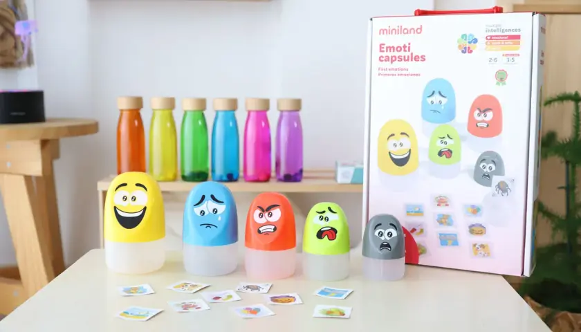 Juguetes para la inteligencia emocional infantil: cápsulas con caras de emociones y tarjetas.