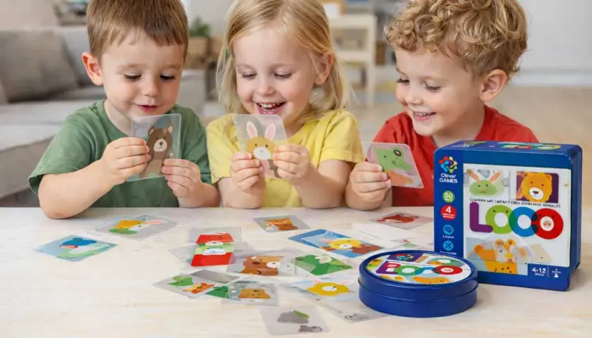 Niños sonríen mientras aprenden a leer jugando con cartas de animales. El juego LOCO fomenta la creatividad y el aprendizaje.