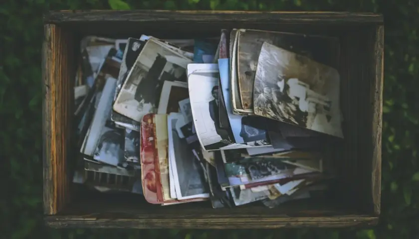 Caja de madera llena de fotos antiguas, como si fueran recuerdos de personas con memoria fotográfica.