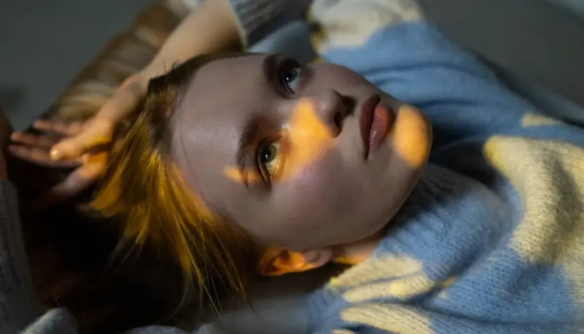 Joven con luz dorada en el rostro, reflexionando sobre técnicas para eliminar pensamientos catastróficos.