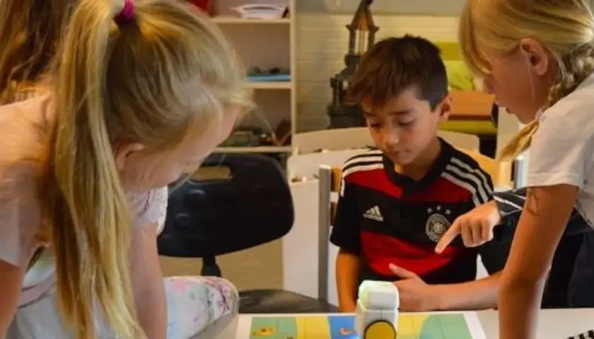 Niños concentrados en deberes de verano originales, programando un robot.