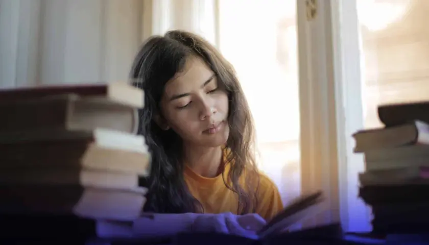Joven concentrada estudiando, rodeada de libros, buscando técnicas para como memorizar fechas importantes.