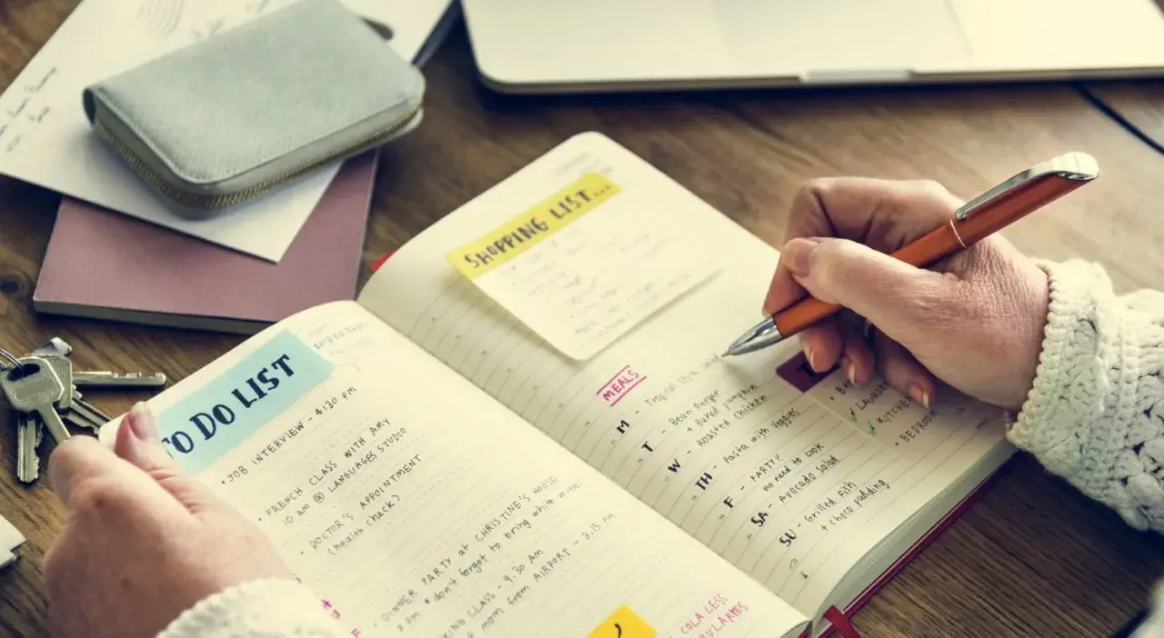 Persona escribe en un diario para aprender a escribir, con listas de tareas y comidas.