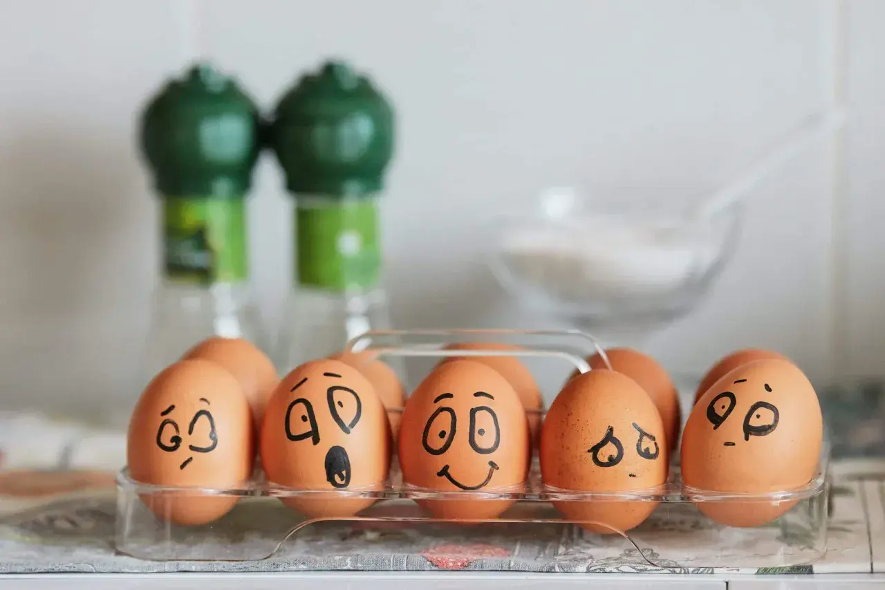 Huevos en una caja con caras dibujadas, mostrando una divertida actividad de las emociones.