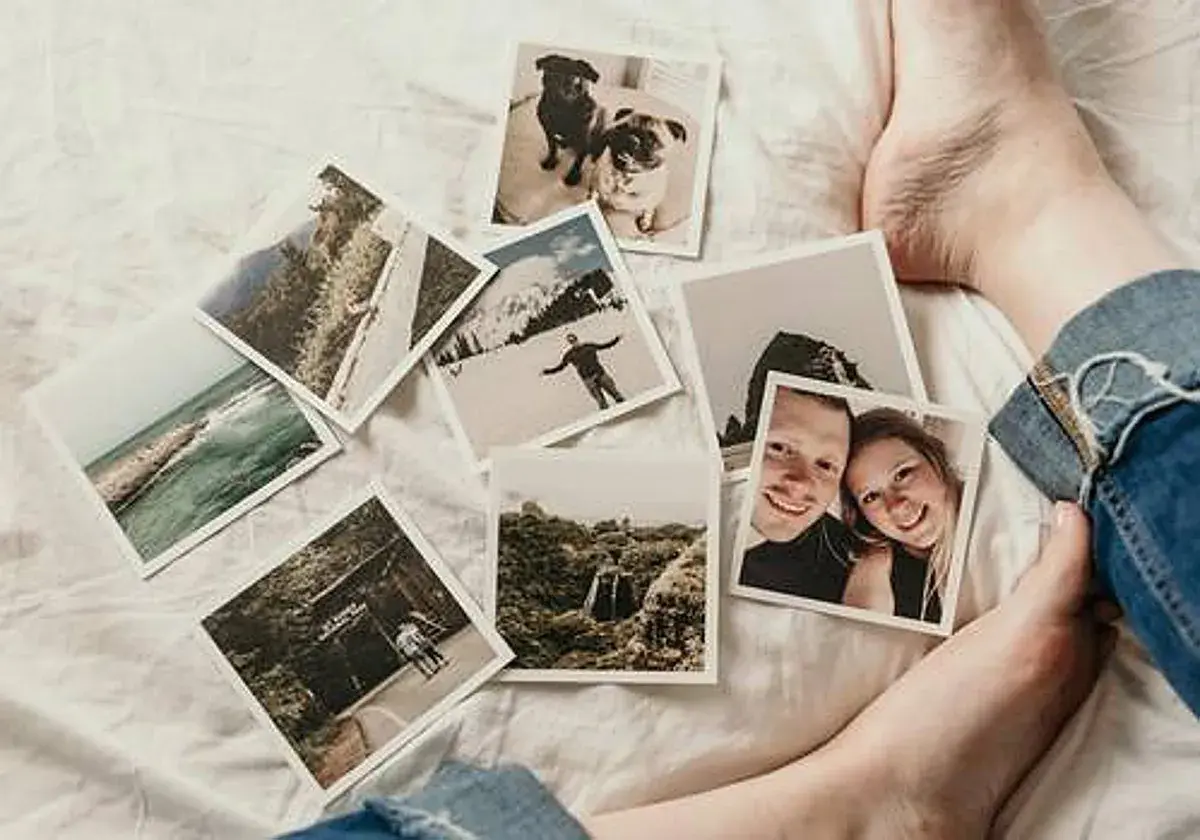 Fotos esparcidas sobre una cama blanca, evocando distorsiones de la memoria: parejas sonrientes, perros, paisajes y aventuras.