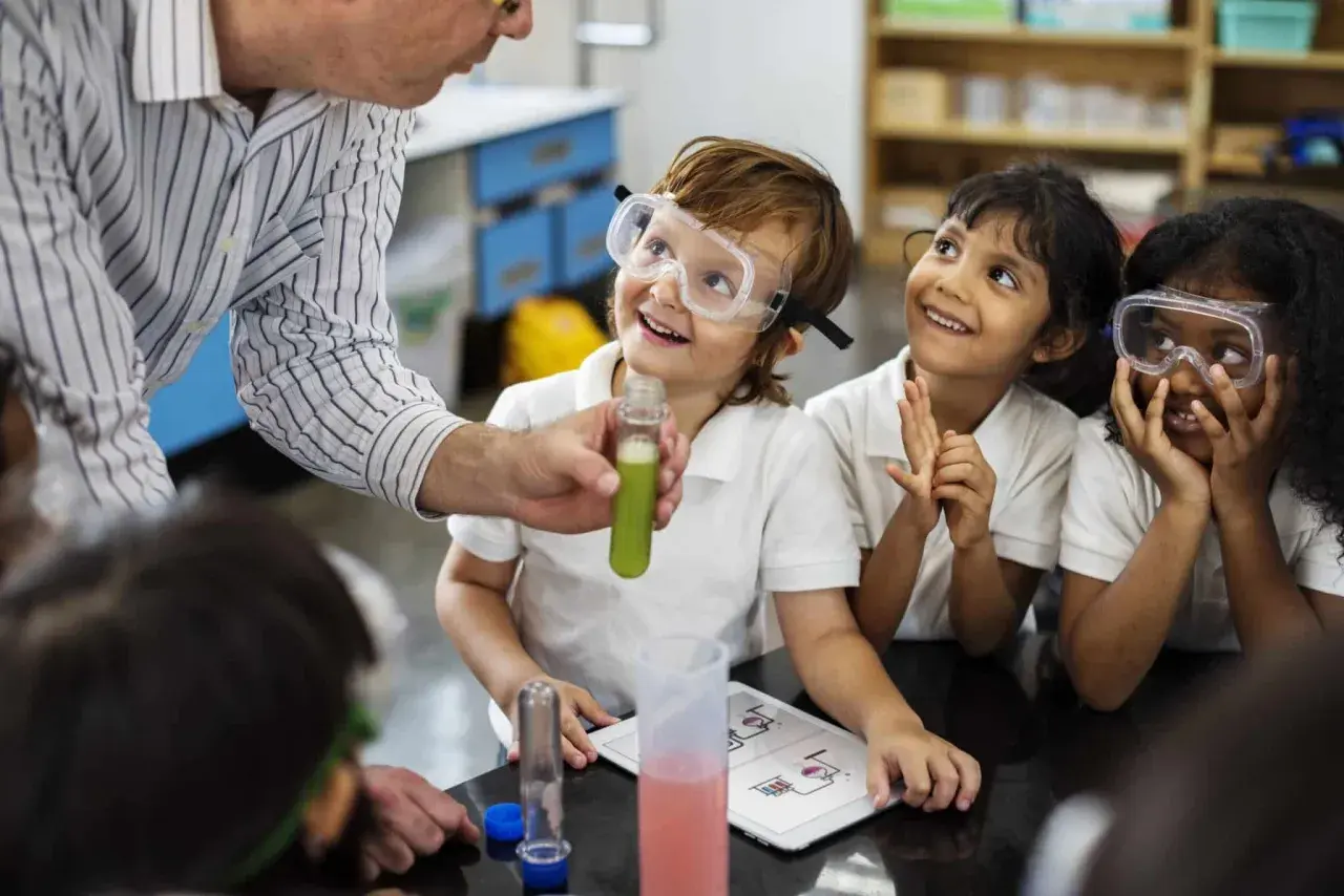 Niños con gafas de seguridad observan un experimento, aprendiendo qué es un STEM.