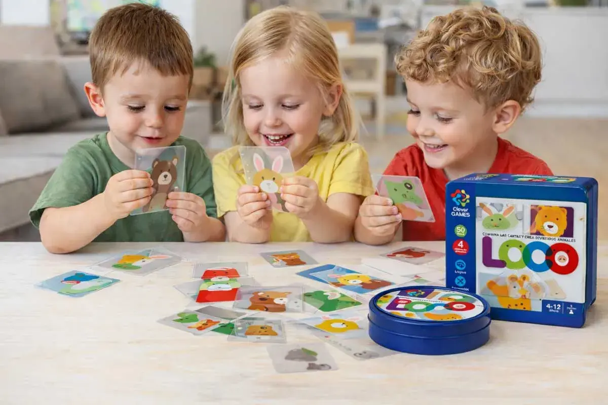 Niños sonríen mientras aprenden a leer jugando con cartas de animales. El juego LOCO fomenta la creatividad y el aprendizaje.