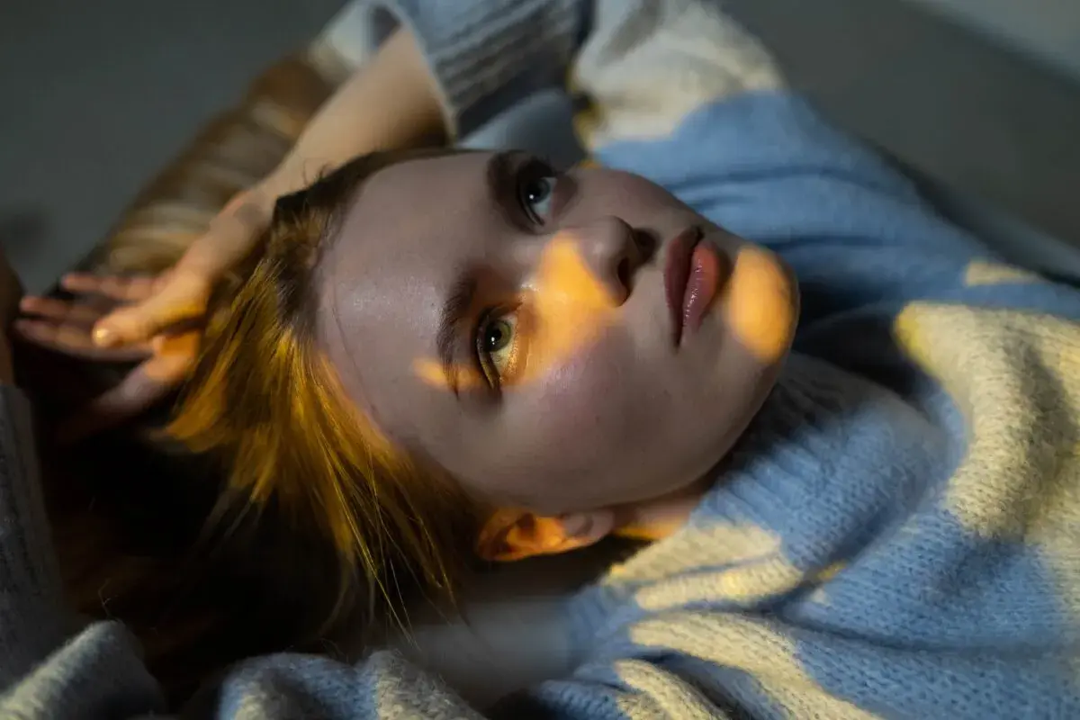 Joven con luz dorada en el rostro, reflexionando sobre técnicas para eliminar pensamientos catastróficos.