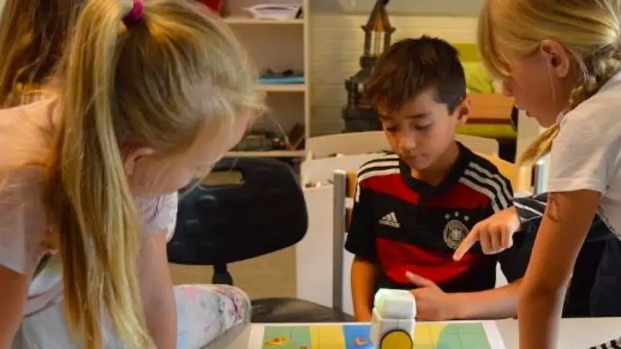 Niños concentrados en deberes de verano originales, programando un robot.