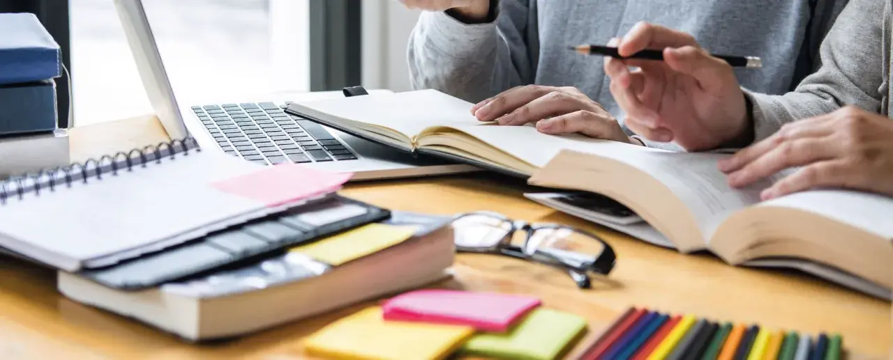 Estudiantes revisando apuntes y libros, preparándose para exámenes. Una guía visual sobre como volver a estudiar y organizar el material.