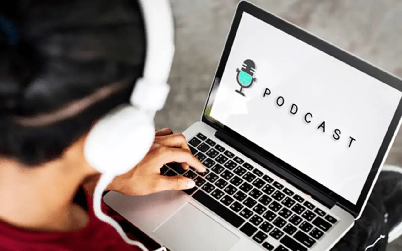 Persona con auriculares escucha un podcast en su port&aacute;til, ideal para estudiar y aprender.