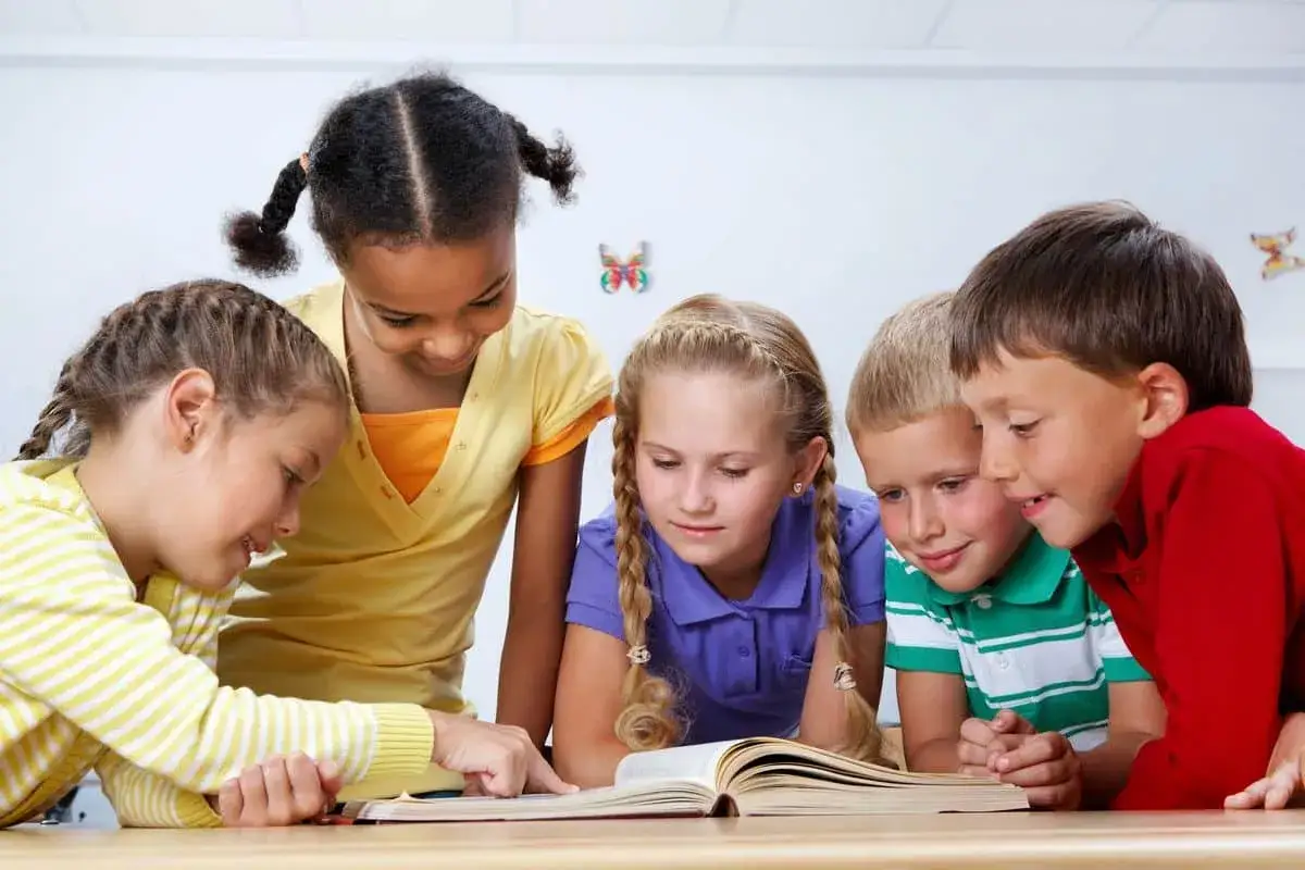 Niños colaborando en un libro, un ejemplo de pedagogía activa donde el aprendizaje es un descubrimiento compartido.