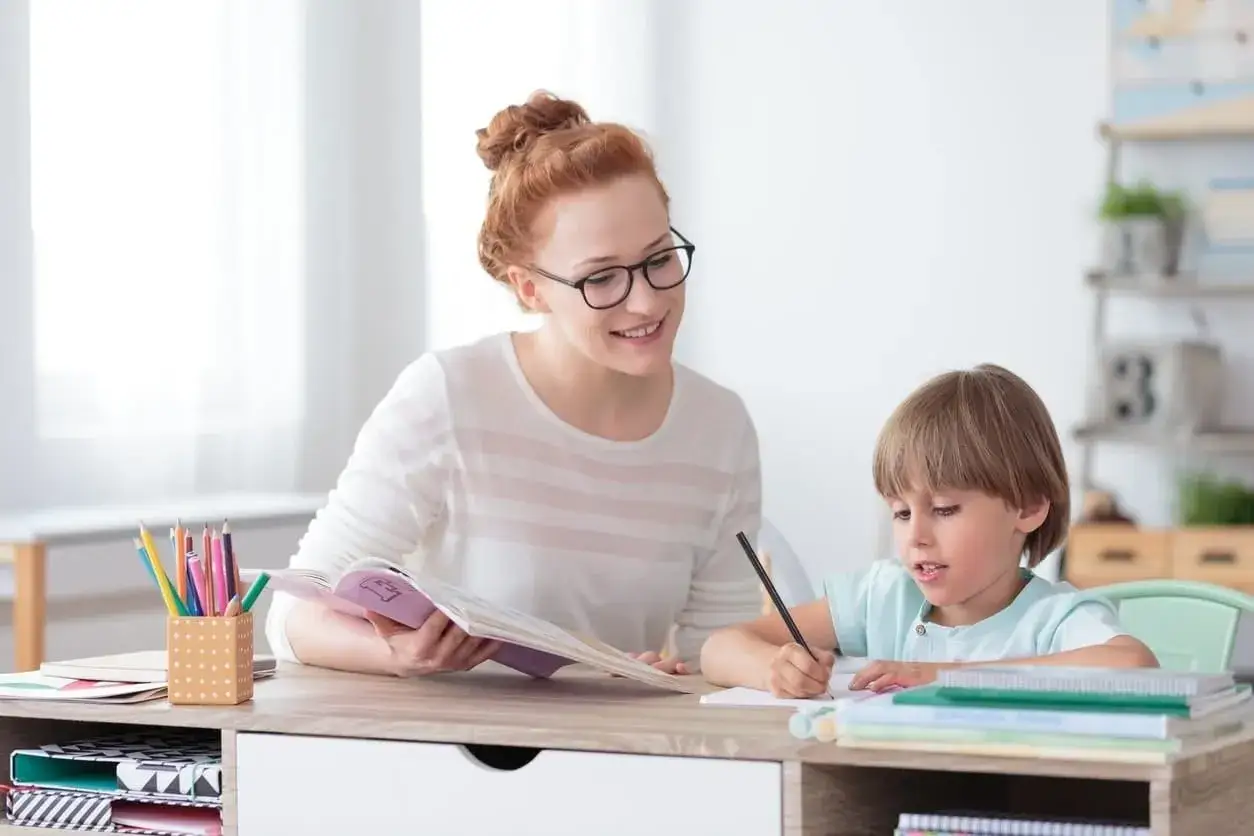 Maestra sonriente ayuda a ni&ntilde;os con dislexia a escribir y leer.