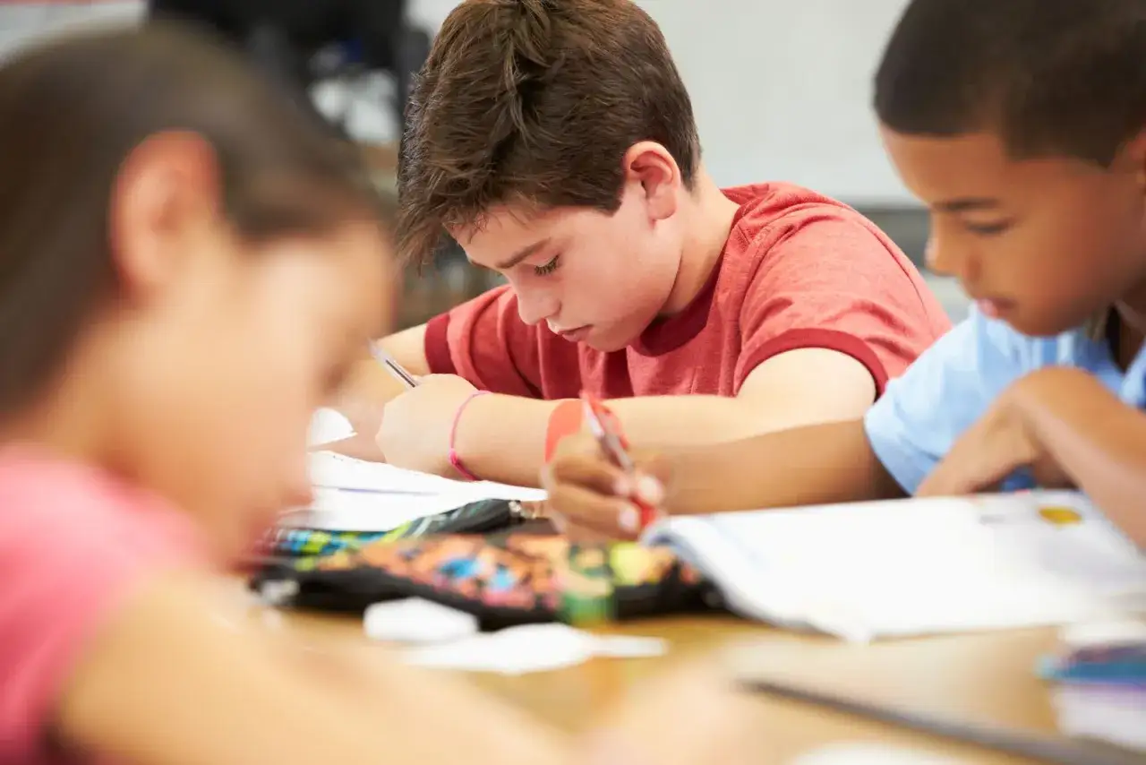 Ni&ntilde;os concentrados en sus tareas, algunos con dificultades lectoescritura, esforz&aacute;ndose por escribir y leer en clase.
